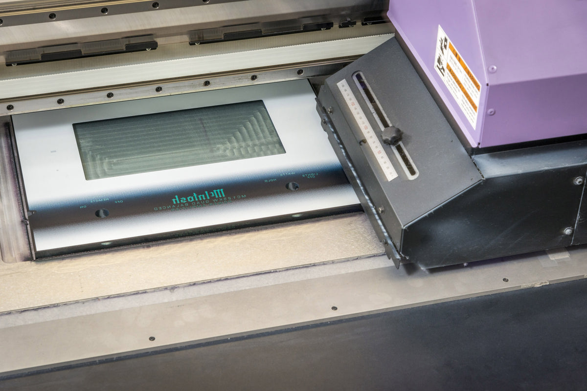 A McIntosh glass front panel leaving the printer, lettered from the back in the factory in Binghamton